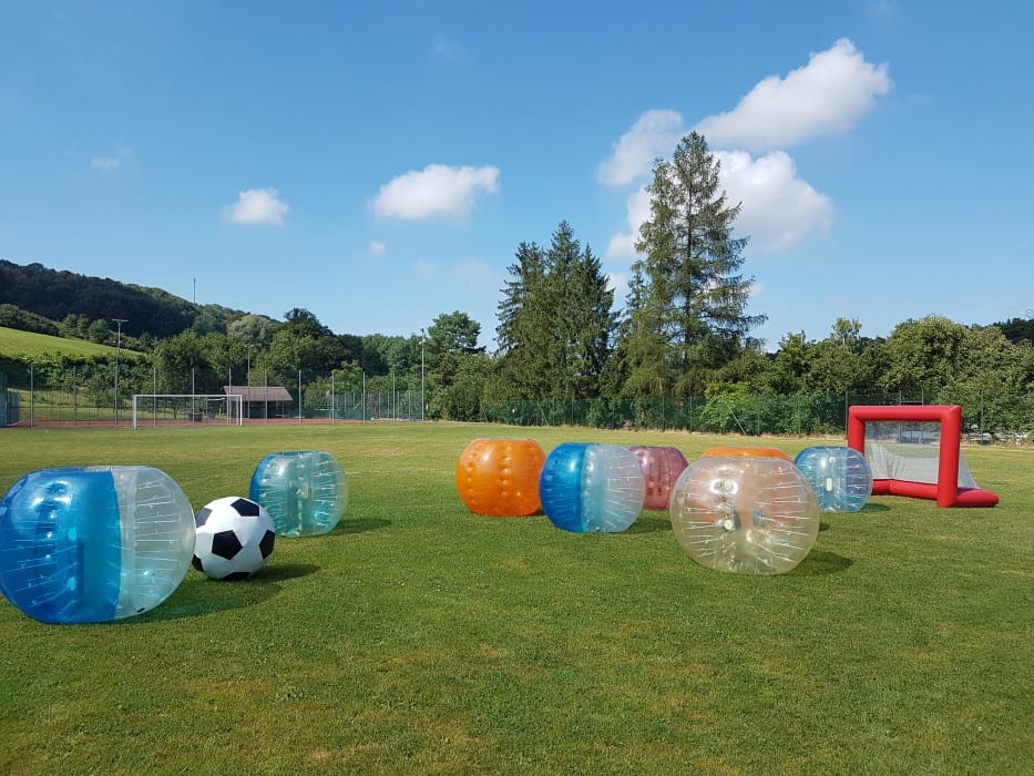Hřiště s nafukovacími balónky a fotbalovým míčem na travnatém hřišti.